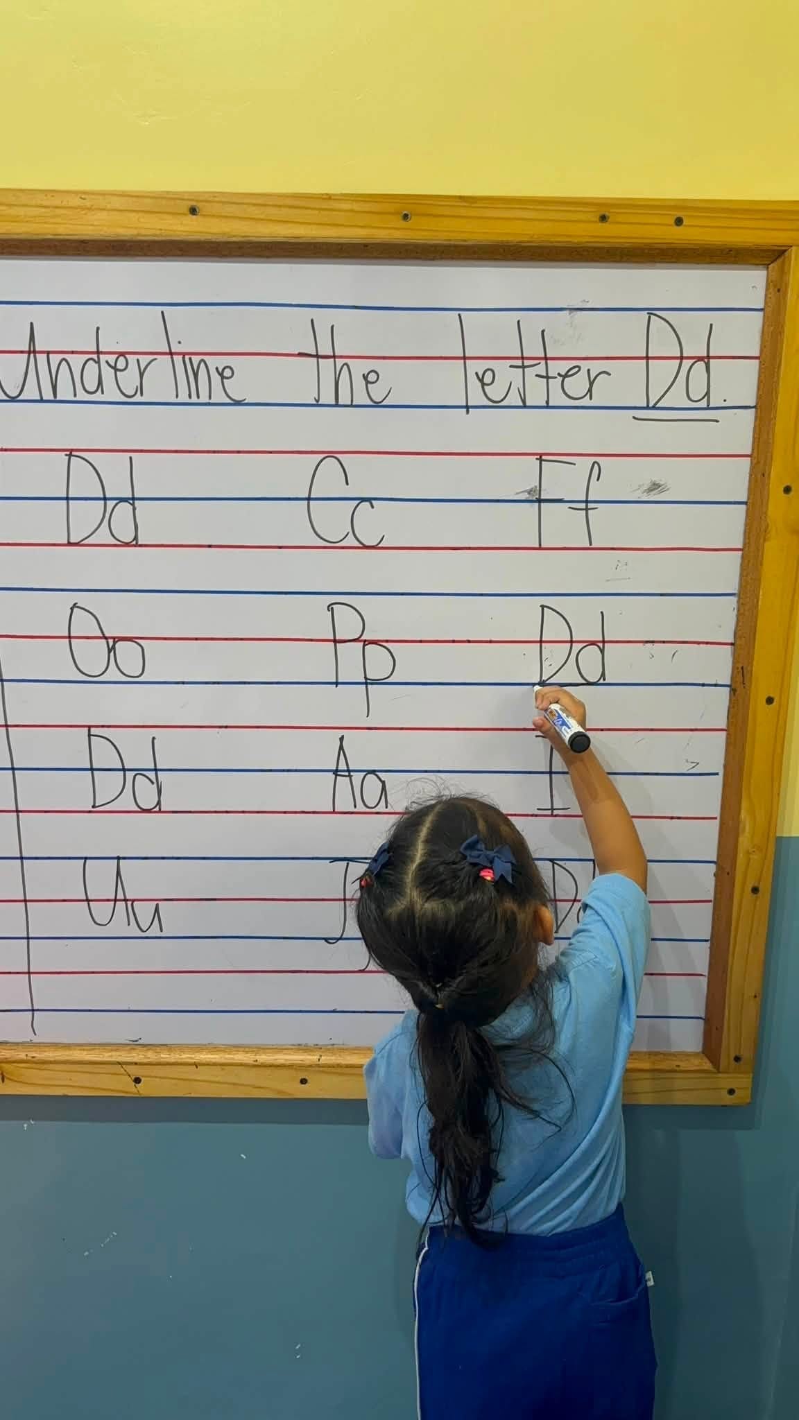 Child underlining the letter Dd on the board